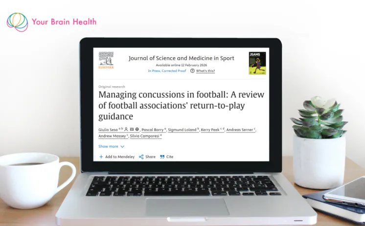 Your Brain Health Research in Focus May 2026 - laptop displaying a Journal of Science and Medicine in Sport paper on concussion return-to-play protocols across FIFA football associations