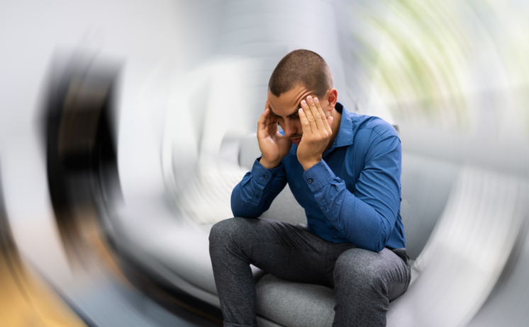 Man holding his head while the room blurs and spins, showing dizziness after concussion